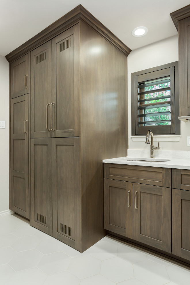 Example of a large transitional single-wall dark wood floor and brown floor utility room design in Dallas with an undermount sink, recessed-panel cabinets, gray cabinets, quartz countertops, white backsplash, quartz backsplash, beige walls, a stacked washer/dryer and white countertops