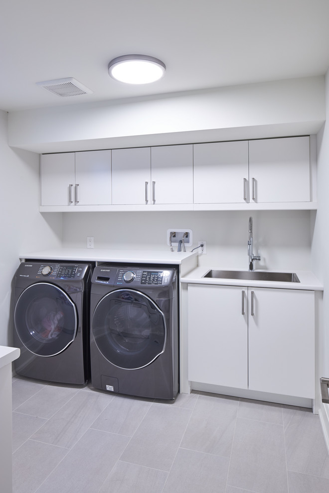 Medium sized contemporary galley separated utility room in Toronto with a submerged sink, flat-panel cabinets, white cabinets, laminate countertops, porcelain flooring, a side by side washer and dryer, grey floors and white worktops.
