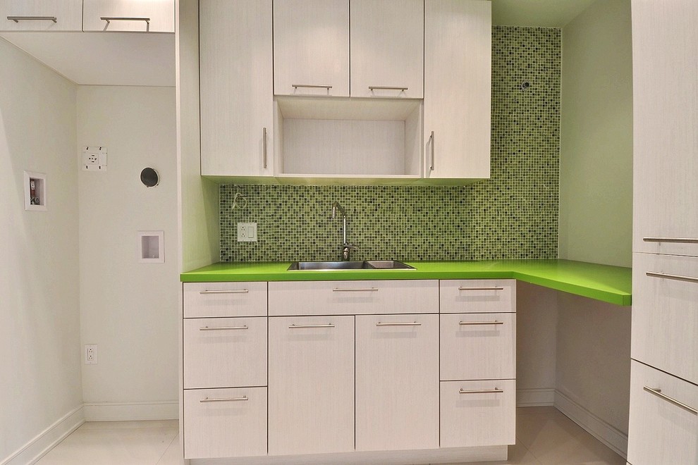 Modern inredning av en mellanstor gröna l-formad grönt tvättstuga enbart för tvätt, med en nedsänkt diskho, släta luckor, skåp i ljust trä, bänkskiva i koppar, gröna väggar, klinkergolv i keramik, en tvättpelare och beiget golv
