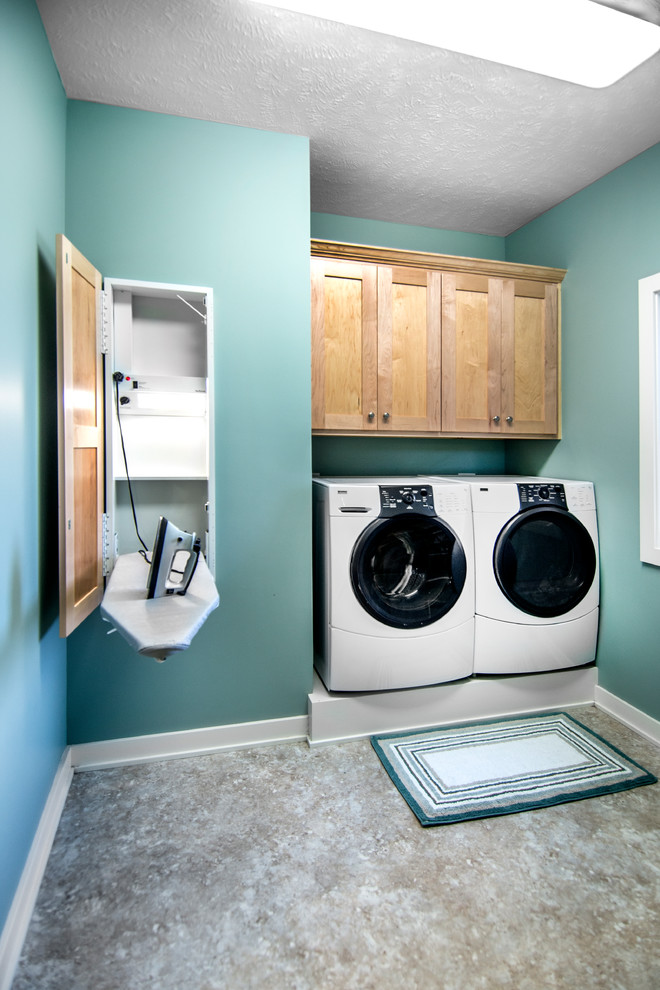 Diseño de cuarto de lavado lineal de estilo americano pequeño con armarios estilo shaker, paredes azules, suelo de linóleo, lavadora y secadora juntas y puertas de armario de madera oscura