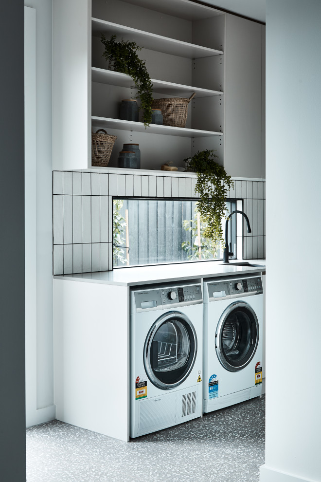 Einzeilige Moderne Waschküche mit Unterbauwaschbecken, flächenbündigen Schrankfronten, grauen Schränken, weißer Wandfarbe, Waschmaschine und Trockner nebeneinander, grauem Boden und grauer Arbeitsplatte in Melbourne