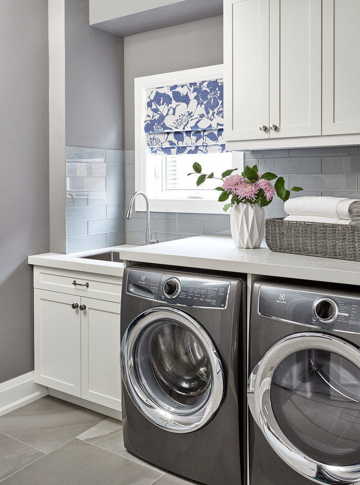 Immagine di una lavanderia tradizionale con lavello sottopiano, ante in stile shaker, ante bianche, pareti grigie, lavatrice e asciugatrice affiancate, pavimento grigio e top bianco