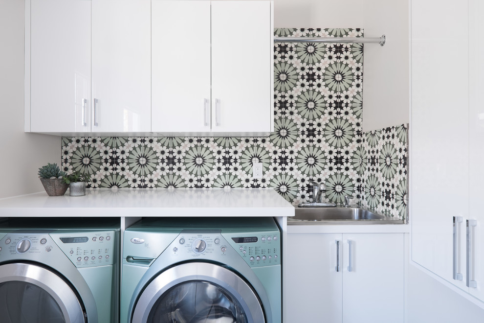 Esempio di una sala lavanderia minimal con ante lisce, ante bianche, top in superficie solida, pareti multicolore, lavello da incasso, lavatrice e asciugatrice affiancate e top bianco