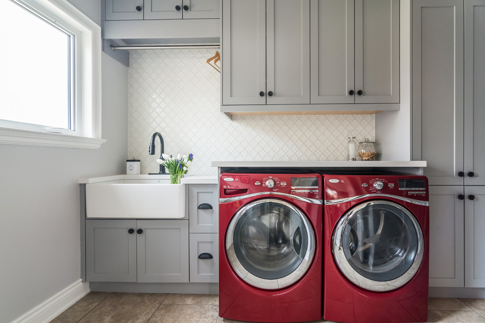 Photo of a classic single-wall separated utility room in Toronto with a belfast sink, shaker cabinets, grey cabinets, grey walls, a side by side washer and dryer, brown floors and white worktops.