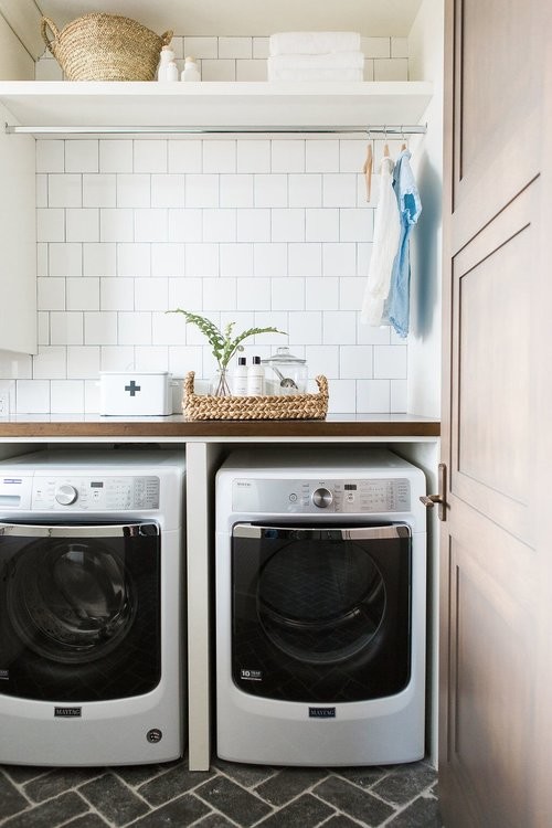 Photo of a medium sized eclectic utility room in Salt Lake City with wood worktops, white walls, brick flooring, a side by side washer and dryer, black floors and brown worktops.