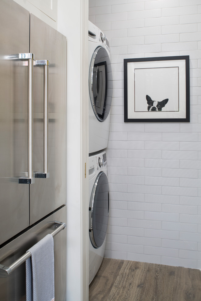Idee per una lavanderia tradizionale di medie dimensioni con pareti bianche, lavatrice e asciugatrice a colonna e pavimento marrone