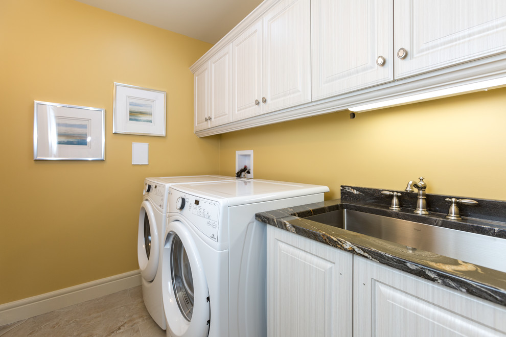 Inredning av en klassisk mellanstor linjär tvättstuga enbart för tvätt, med en undermonterad diskho, luckor med upphöjd panel, vita skåp, bänkskiva i koppar, gula väggar, vinylgolv och en tvättmaskin och torktumlare bredvid varandra