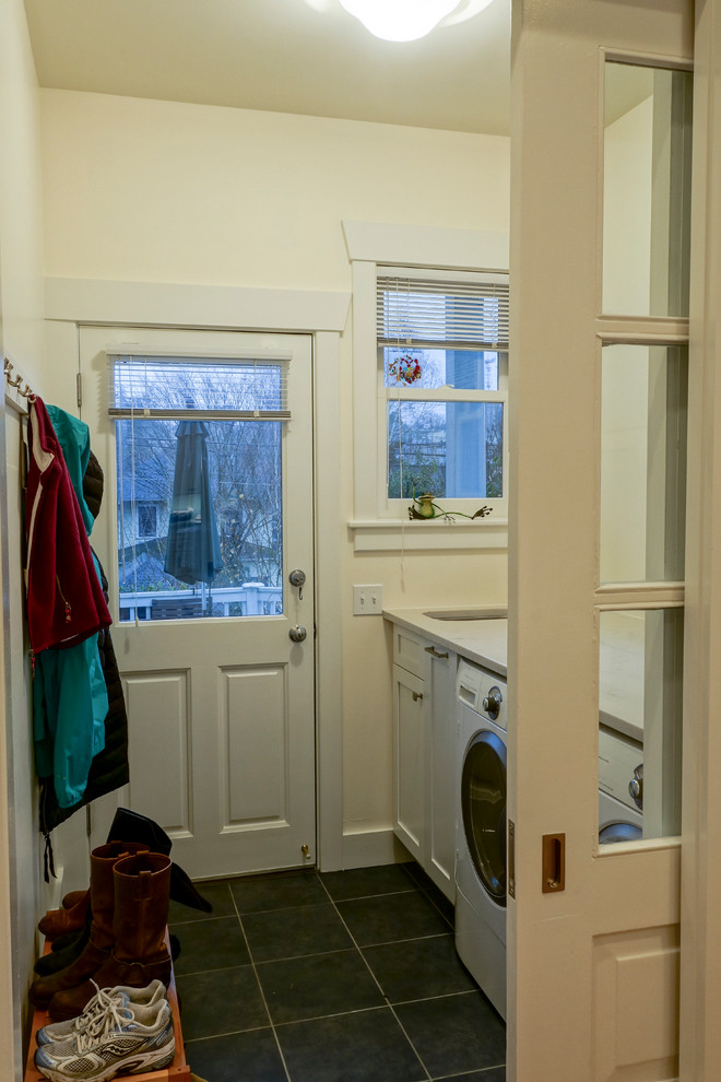 シアトルにある低価格の小さなトラディショナルスタイルのおしゃれな家事室 (I型、シングルシンク、シェーカースタイル扉のキャビネット、白いキャビネット、珪岩カウンター、黄色い壁、スレートの床、左右配置の洗濯機・乾燥機) の写真