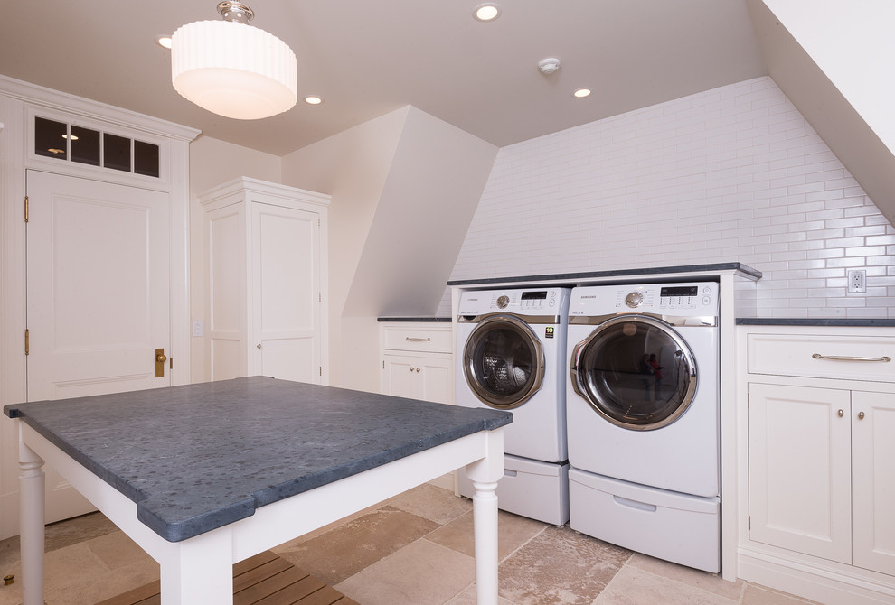 Foto di una sala lavanderia stile marinaro con ante bianche, pavimento in pietra calcarea e lavatrice e asciugatrice affiancate