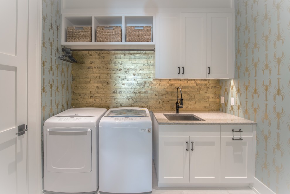 Exempel på en liten klassisk grå linjär grått tvättstuga enbart för tvätt, med en enkel diskho, skåp i shakerstil, vita skåp, bänkskiva i kvarts, blå väggar, klinkergolv i porslin, en tvättmaskin och torktumlare bredvid varandra och vitt golv