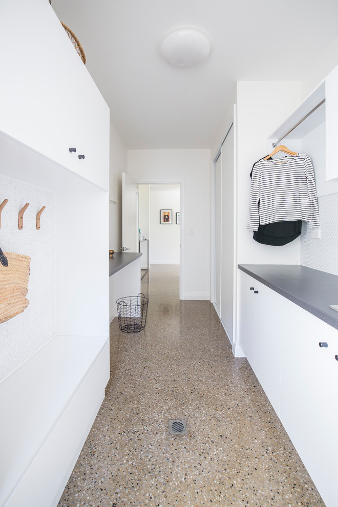 Immagine di una grande lavanderia multiuso minimal con ante lisce, ante bianche, pareti bianche e pavimento in cemento