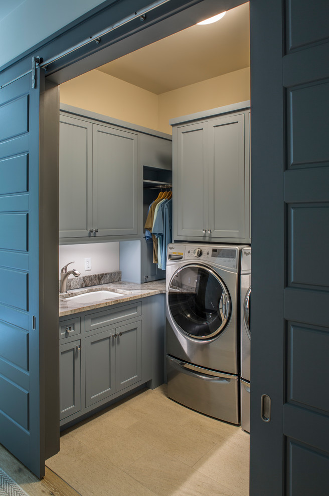 Ispirazione per una piccola sala lavanderia minimalista con lavello sottopiano, ante con riquadro incassato, ante blu, top in marmo, pareti beige, lavatrice e asciugatrice affiancate, pavimento beige e top marrone