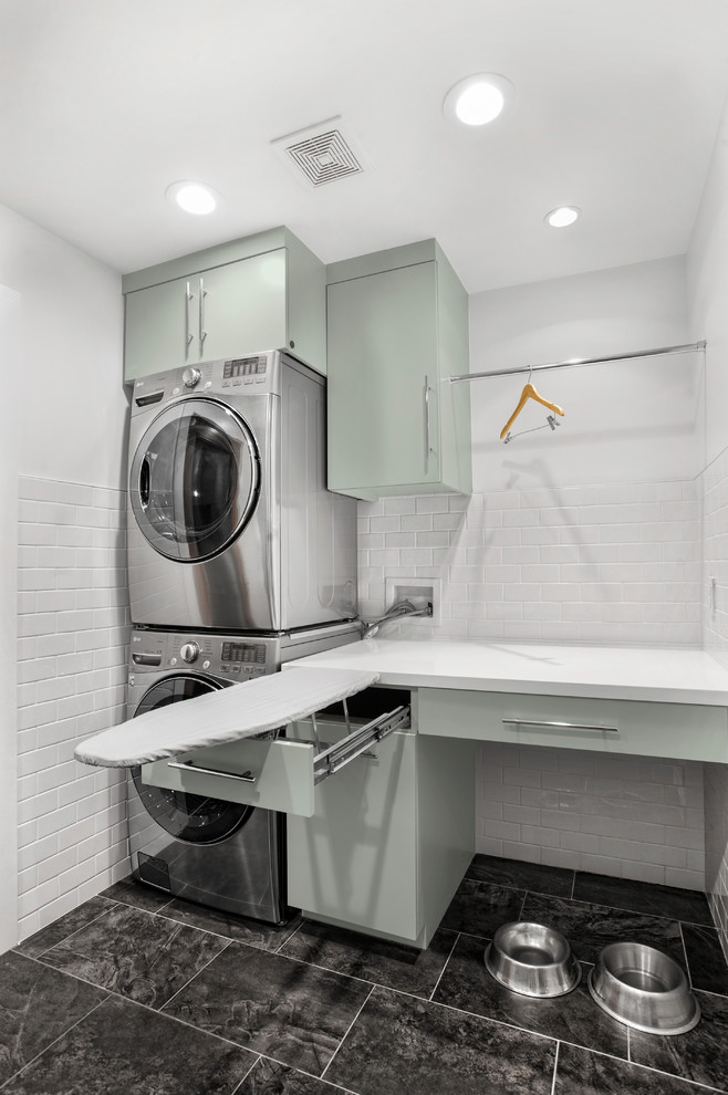 Inredning av en retro mellanstor linjär tvättstuga enbart för tvätt, med släta luckor, bänkskiva i koppar, vita väggar, klinkergolv i porslin, en tvättpelare, grått golv och gröna skåp