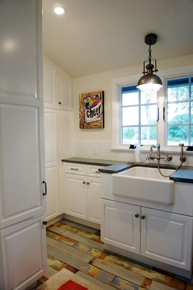 Cottage chic u-shaped painted wood floor dedicated laundry room photo in San Diego with a farmhouse sink, raised-panel cabinets, white cabinets, soapstone countertops, beige walls and a side-by-side washer/dryer