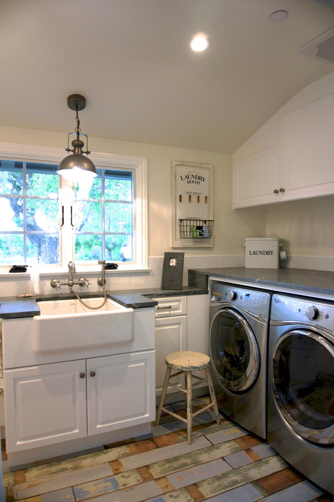 Exempel på en shabby chic-inspirerad u-formad tvättstuga enbart för tvätt, med en rustik diskho, luckor med upphöjd panel, vita skåp, bänkskiva i täljsten, beige väggar, målat trägolv och en tvättmaskin och torktumlare bredvid varandra