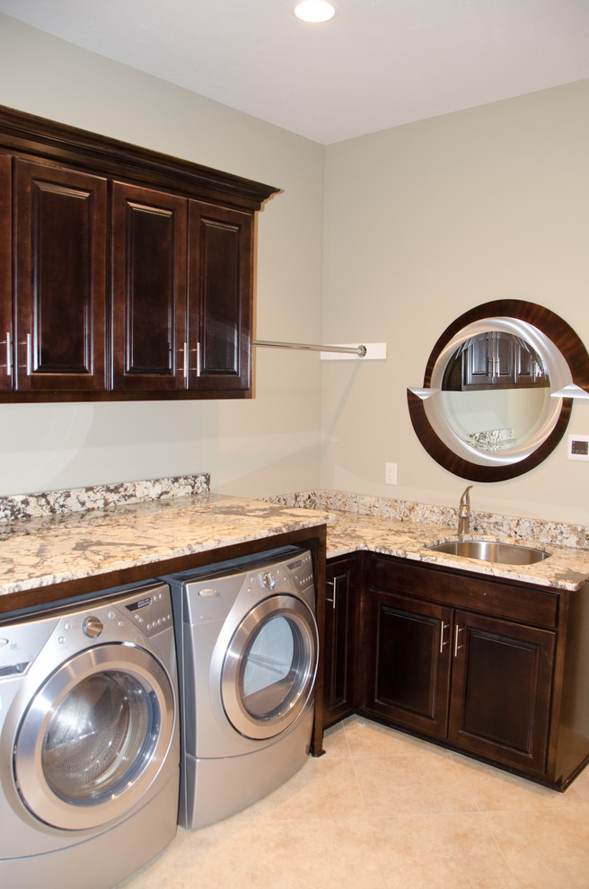 Dedicated laundry room - mid-sized transitional l-shaped ceramic tile dedicated laundry room idea in Omaha with an undermount sink, raised-panel cabinets, dark wood cabinets, granite countertops, beige walls and a side-by-side washer/dryer