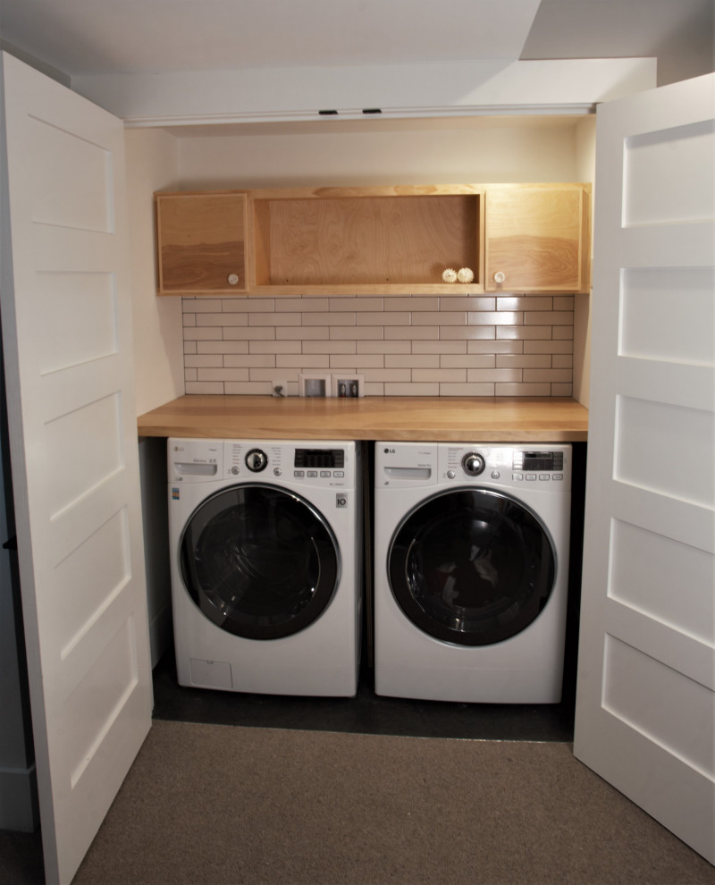 Diseño de armario lavadero lineal actual pequeño con armarios abiertos, puertas de armario de madera clara, encimera de madera, lavadora y secadora juntas y encimeras beige