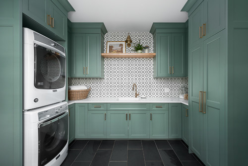 Cabinet color trends featuring modern green cabinetry with brass handles in a stylish laundry room design.