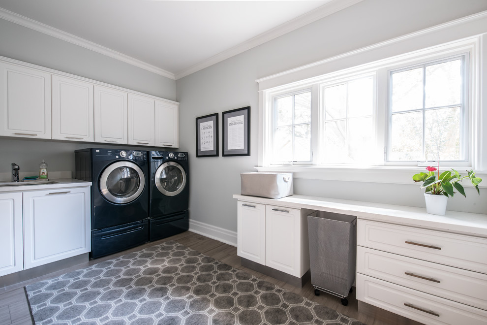 This is an example of a large traditional l-shaped separated utility room in Toronto with raised-panel cabinets, white cabinets, quartz worktops, porcelain flooring and a side by side washer and dryer.