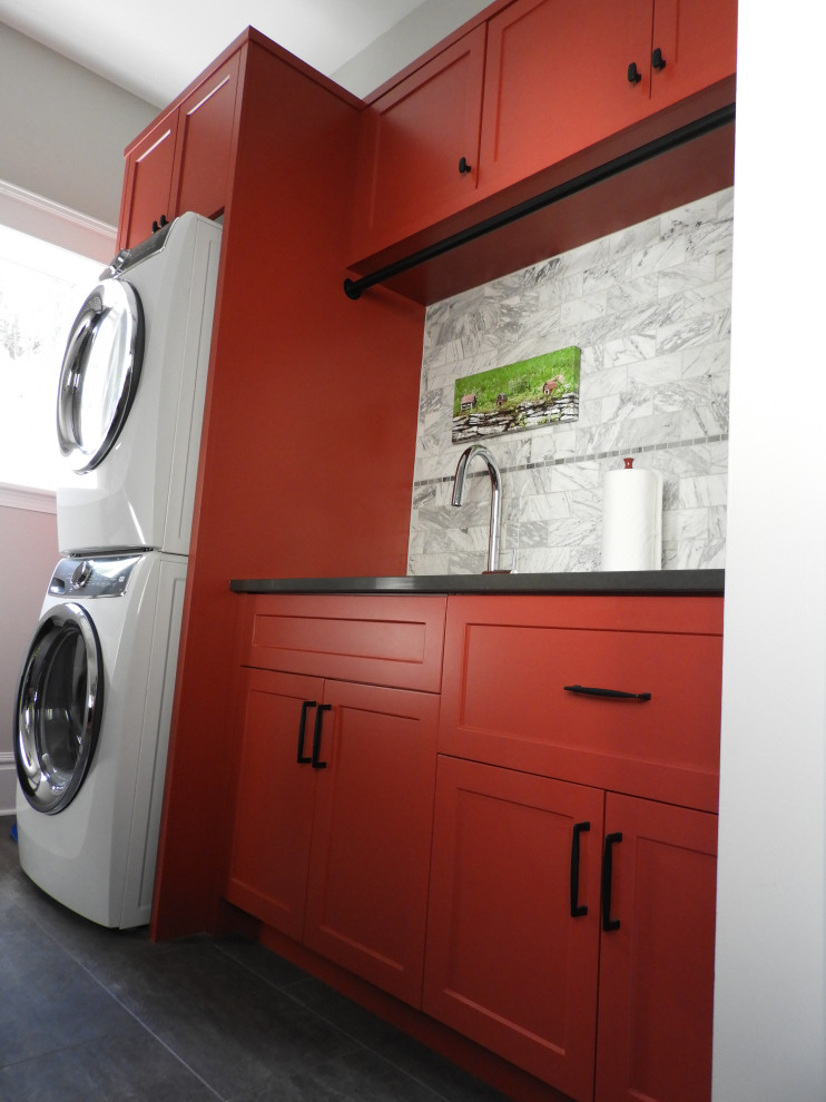 トロントにあるお手頃価格の小さなトランジショナルスタイルのおしゃれな家事室 (I型、アンダーカウンターシンク、シェーカースタイル扉のキャビネット、赤いキャビネット、クオーツストーンカウンター、白いキッチンパネル、石タイルのキッチンパネル、白い壁、セラミックタイルの床、上下配置の洗濯機・乾燥機、グレーの床、黒いキッチンカウンター、塗装板張りの壁) の写真