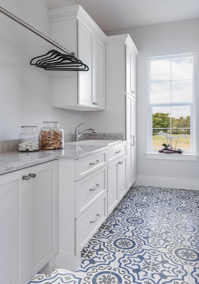 Inspiration for a large nautical single-wall separated utility room in Tampa with a built-in sink, shaker cabinets, white cabinets, marble worktops, white splashback, porcelain flooring, a concealed washer and dryer, multi-coloured floors, grey worktops and a vaulted ceiling.