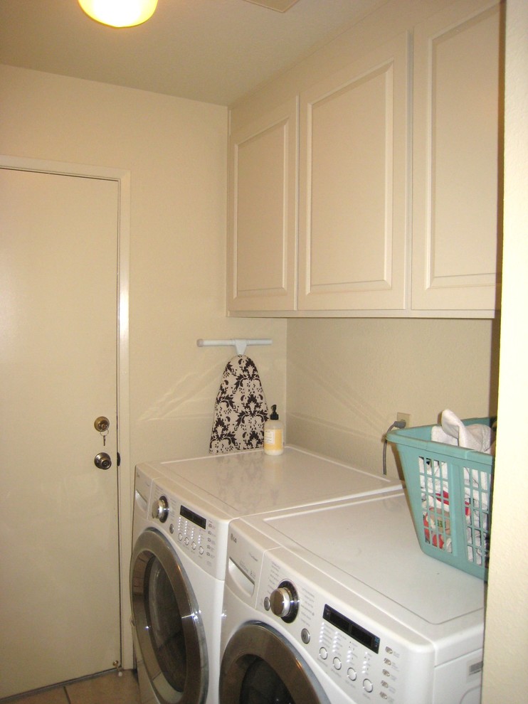 Inredning av en klassisk liten linjär tvättstuga enbart för tvätt, med luckor med upphöjd panel, vita skåp, vita väggar, klinkergolv i porslin och en tvättmaskin och torktumlare bredvid varandra