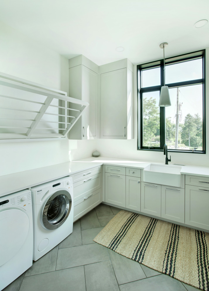 Design ideas for a large contemporary u-shaped utility room in Toronto with a belfast sink, shaker cabinets, white cabinets, quartz worktops, white walls, a side by side washer and dryer and white worktops.