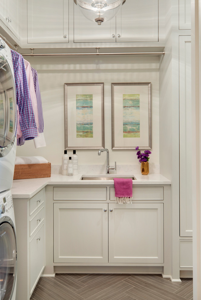 Klassisk inredning av en liten l-formad tvättstuga enbart för tvätt, med en undermonterad diskho, luckor med infälld panel, vita skåp, vita väggar och en tvättpelare