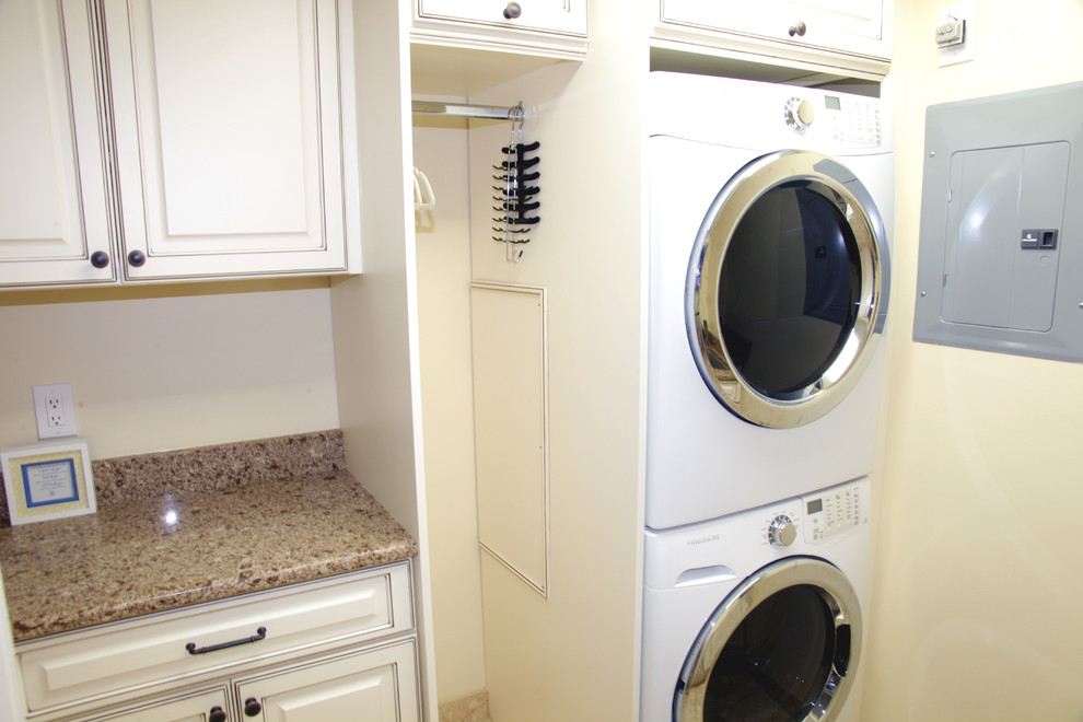 This is an example of a traditional single-wall separated utility room in Miami with raised-panel cabinets, white cabinets, marble worktops, marble flooring and a stacked washer and dryer.