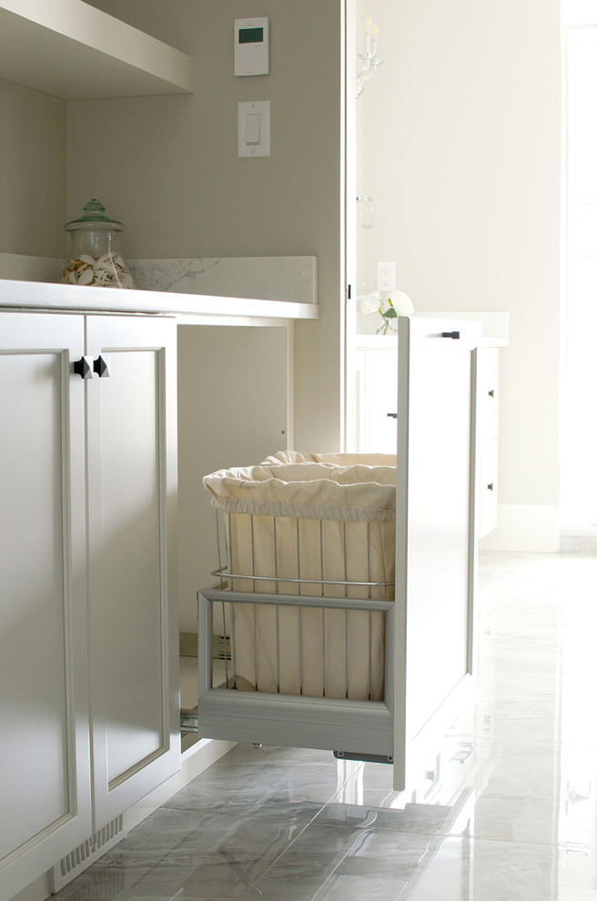 Foto på en mellanstor lantlig vita tvättstuga enbart för tvätt, med luckor med infälld panel, vita skåp, marmorbänkskiva, grå väggar och grått golv