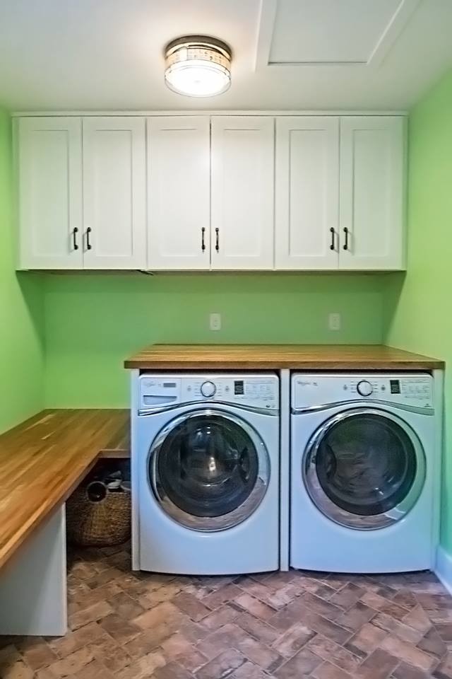 Foto di una lavanderia chic di medie dimensioni con ante in stile shaker, ante bianche, top in legno, pareti verdi, pavimento in mattoni e lavatrice e asciugatrice affiancate