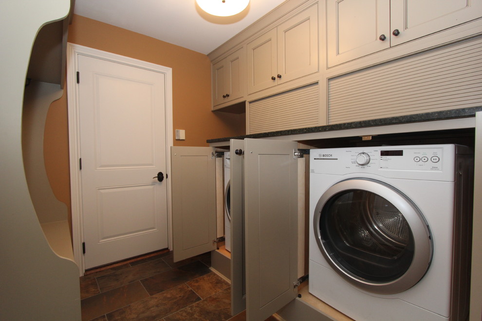 Esempio di una lavanderia multiuso chic di medie dimensioni con lavello sottopiano, ante a filo, top in granito, pavimento con piastrelle in ceramica, lavatrice e asciugatrice nascoste e pareti marroni