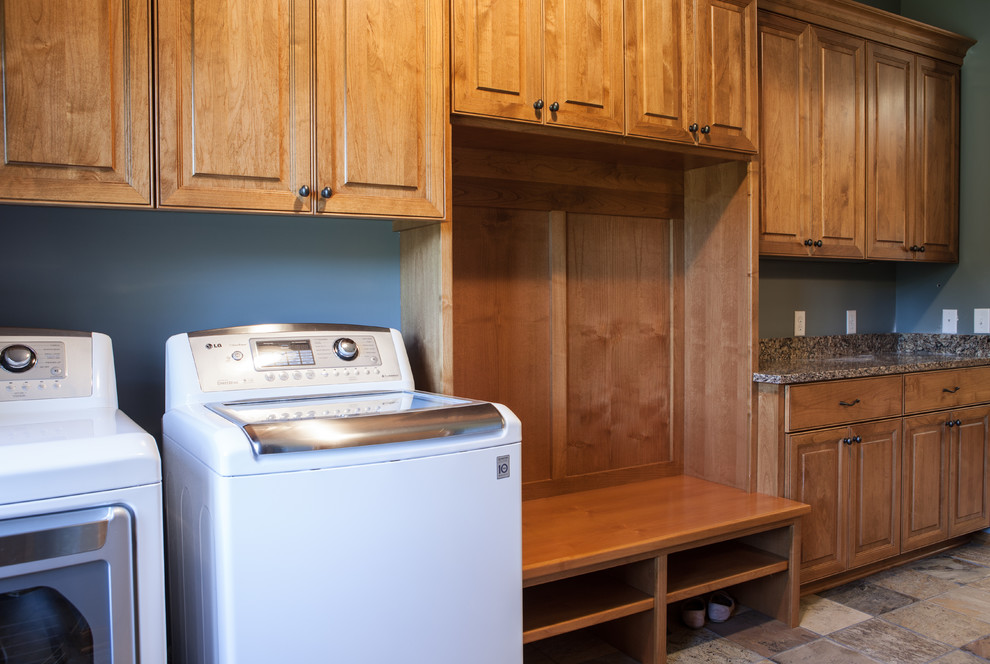 Foto på ett mellanstort vintage linjärt grovkök, med luckor med upphöjd panel, skåp i mellenmörkt trä, bänkskiva i kvarts, blå väggar, skiffergolv och en tvättmaskin och torktumlare bredvid varandra