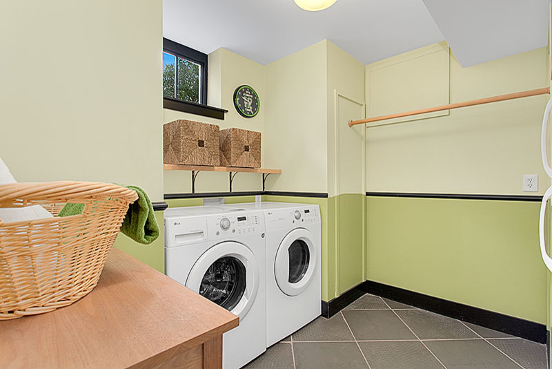 Inspiration för asiatiska tvättstugor enbart för tvätt, med gröna väggar, en tvättmaskin och torktumlare bredvid varandra och grått golv