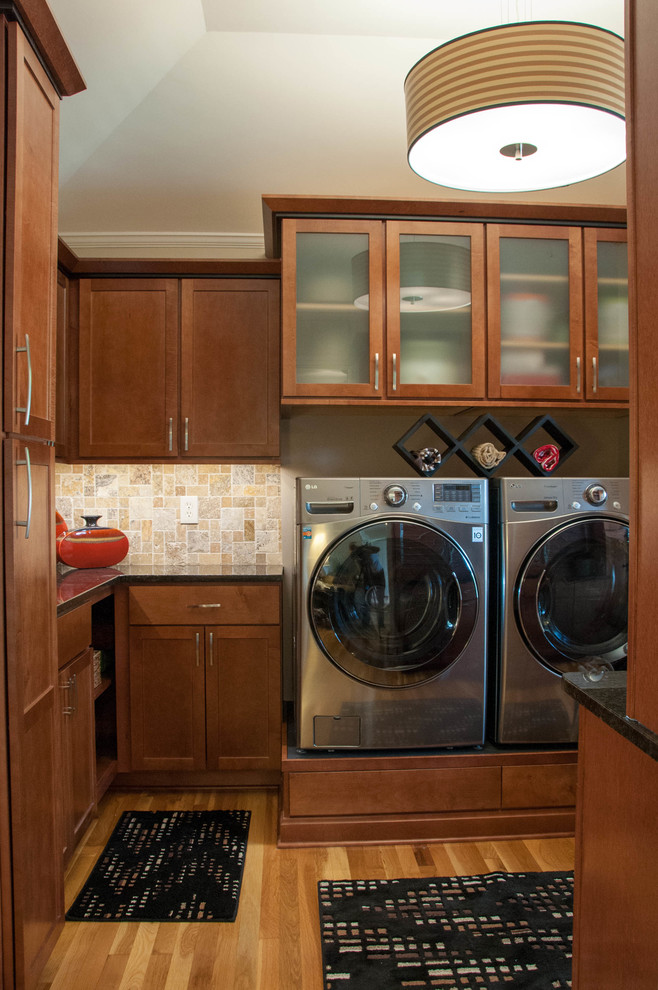 Mid-sized elegant l-shaped medium tone wood floor dedicated laundry room photo in Kansas City with an undermount sink, shaker cabinets, medium tone wood cabinets, granite countertops, beige walls and a side-by-side washer/dryer