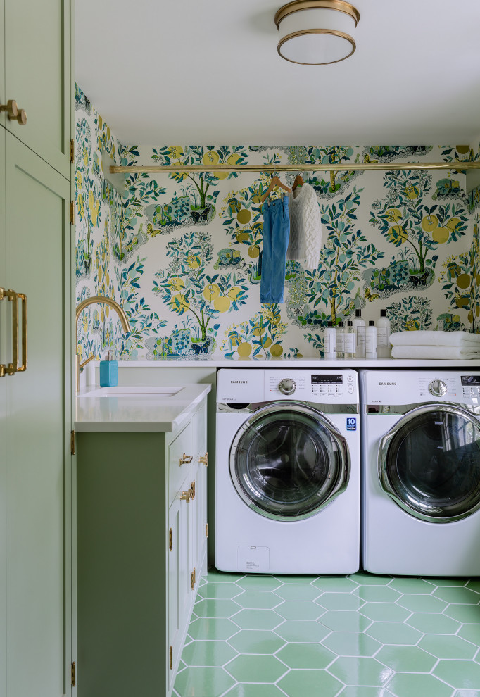 Klassische Waschküche in L-Form mit Schrankfronten im Shaker-Stil, grünen Schränken, bunten Wänden, Waschmaschine und Trockner nebeneinander, grünem Boden, weißer Arbeitsplatte und Tapetenwänden in Boston