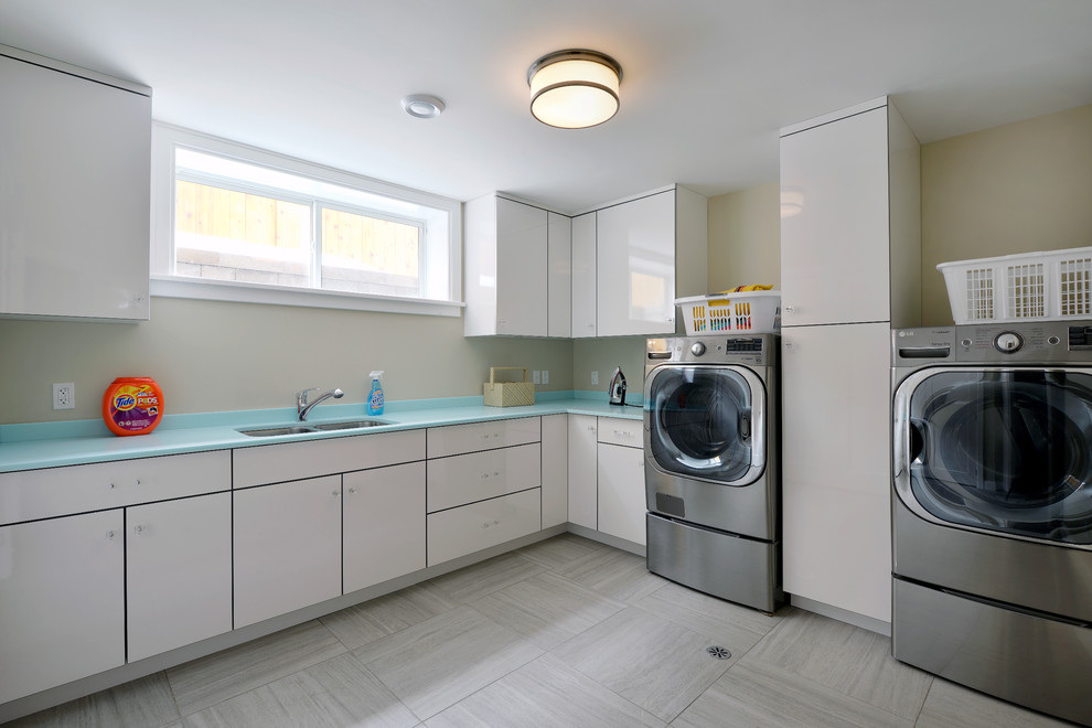 Diseño de cuarto de lavado en L contemporáneo con fregadero bajoencimera, armarios con paneles lisos, puertas de armario blancas, paredes beige, lavadora y secadora juntas, suelo gris y encimeras azules