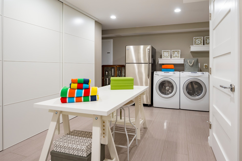 ワシントンD.C.にあるお手頃価格の広いコンテンポラリースタイルのおしゃれな家事室 (グレーの壁、左右配置の洗濯機・乾燥機、グレーの床、ラミネートの床) の写真