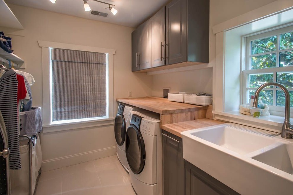 Foto di una sala lavanderia classica con lavello stile country, top in legno, pavimento con piastrelle in ceramica e lavatrice e asciugatrice affiancate