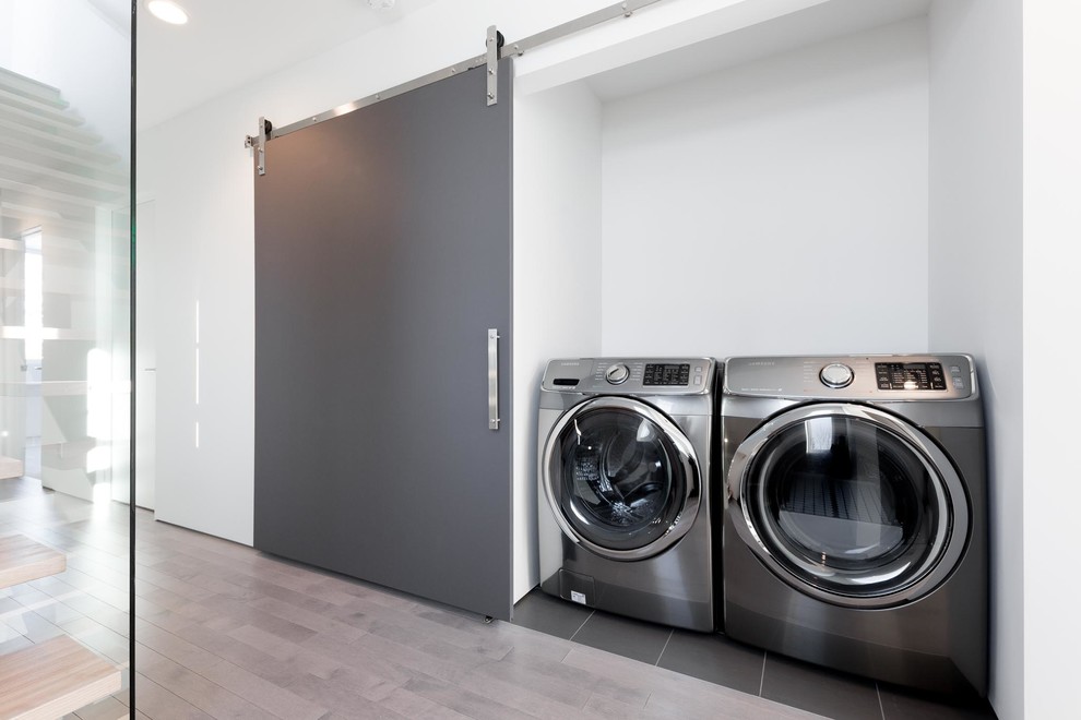 Esempio di un piccolo ripostiglio-lavanderia minimalista con pareti bianche, pavimento con piastrelle in ceramica, lavatrice e asciugatrice affiancate e pavimento grigio
