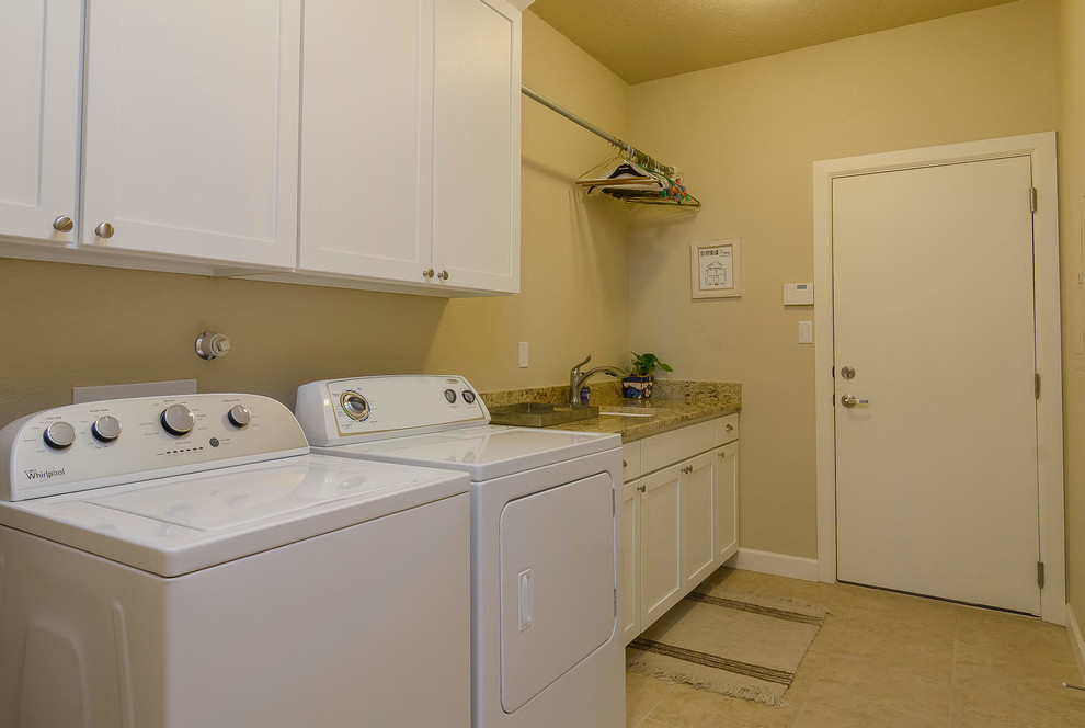 Einzeilige, Mittelgroße Klassische Waschküche mit Unterbauwaschbecken, Schrankfronten im Shaker-Stil, weißen Schränken, Granit-Arbeitsplatte, beiger Wandfarbe, Travertin und Waschmaschine und Trockner nebeneinander in Albuquerque