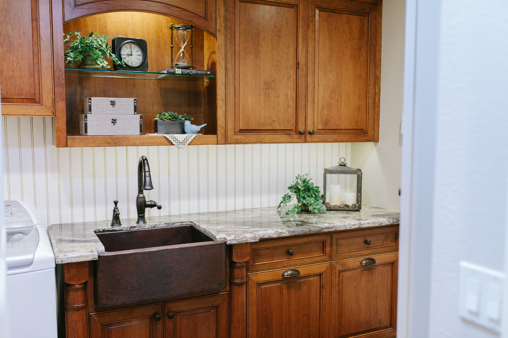 Mid-sized elegant single-wall medium tone wood floor dedicated laundry room photo in Sacramento with a farmhouse sink, raised-panel cabinets, medium tone wood cabinets, granite countertops, white walls and a side-by-side washer/dryer