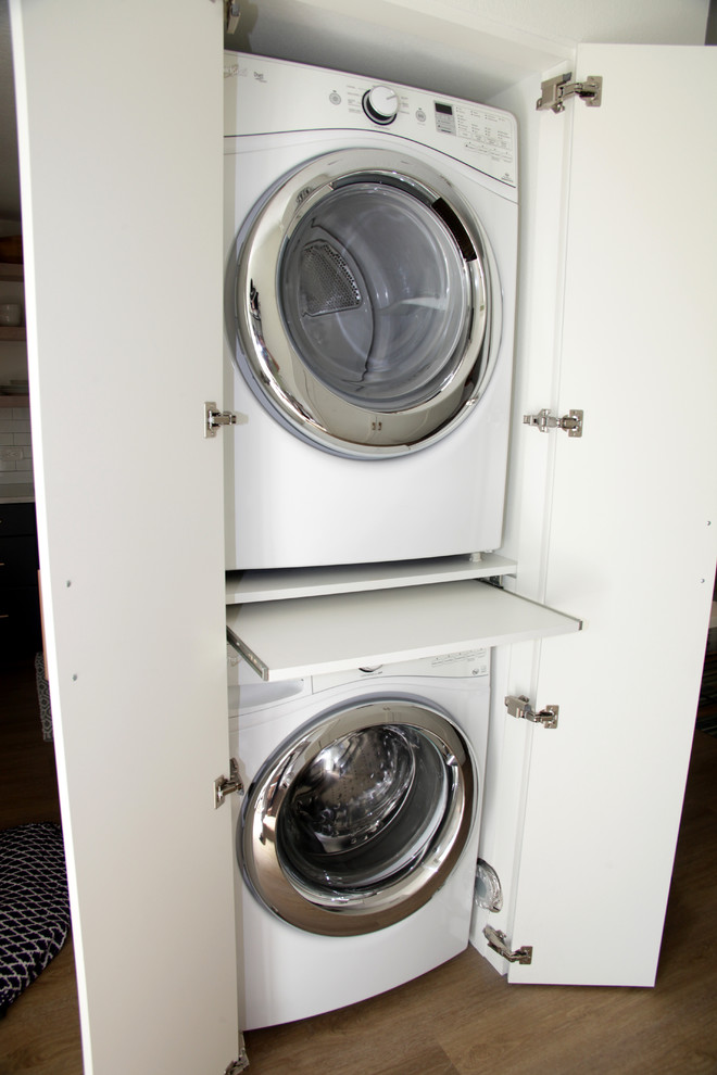 Maritimer Hauswirtschaftsraum mit Waschmaschinenschrank, flächenbündigen Schrankfronten, weißen Schränken und Waschmaschine und Trockner gestapelt in Miami