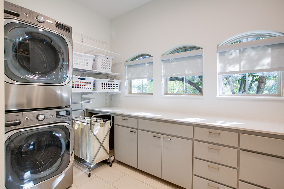 Exempel på en stor modern tvättstuga, med släta luckor, grå skåp, vita väggar, en tvättpelare, bänkskiva i koppar och vinylgolv
