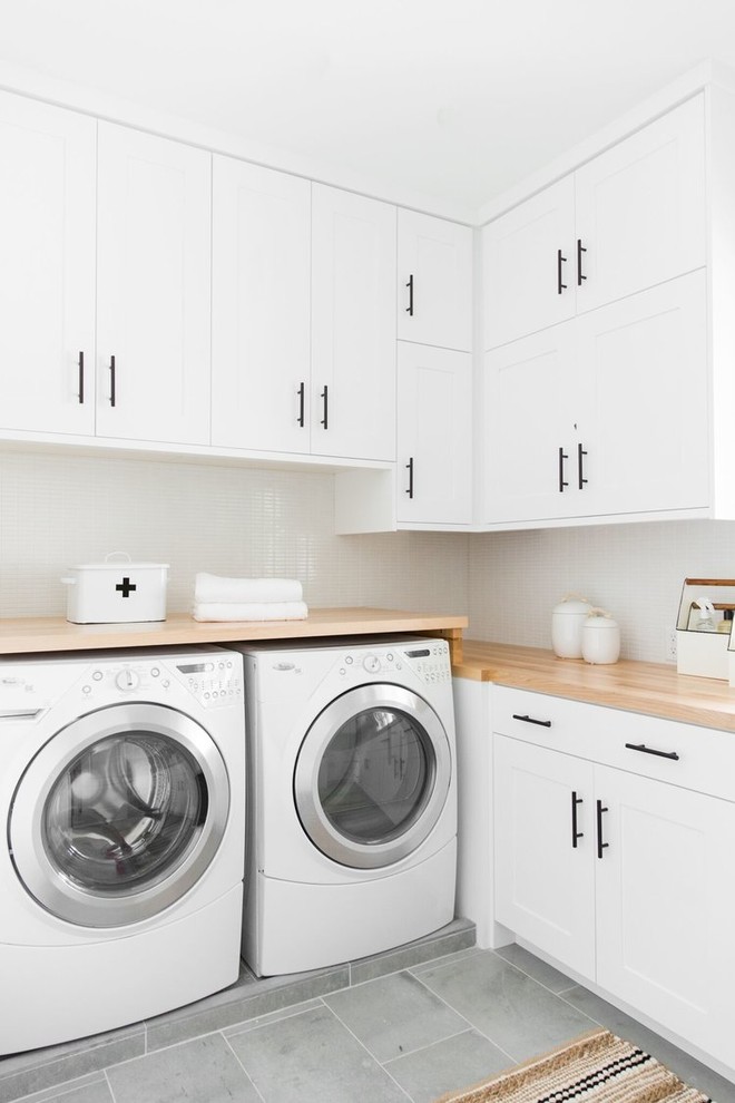 Exempel på en mellanstor klassisk tvättstuga enbart för tvätt, med en nedsänkt diskho, skåp i shakerstil, vita skåp, träbänkskiva, vita väggar och en tvättmaskin och torktumlare bredvid varandra