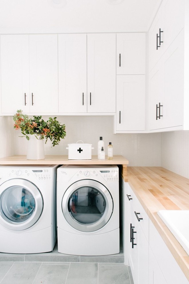 Ejemplo de cuarto de lavado clásico renovado de tamaño medio con fregadero encastrado, armarios estilo shaker, puertas de armario blancas, encimera de madera, paredes blancas y lavadora y secadora juntas