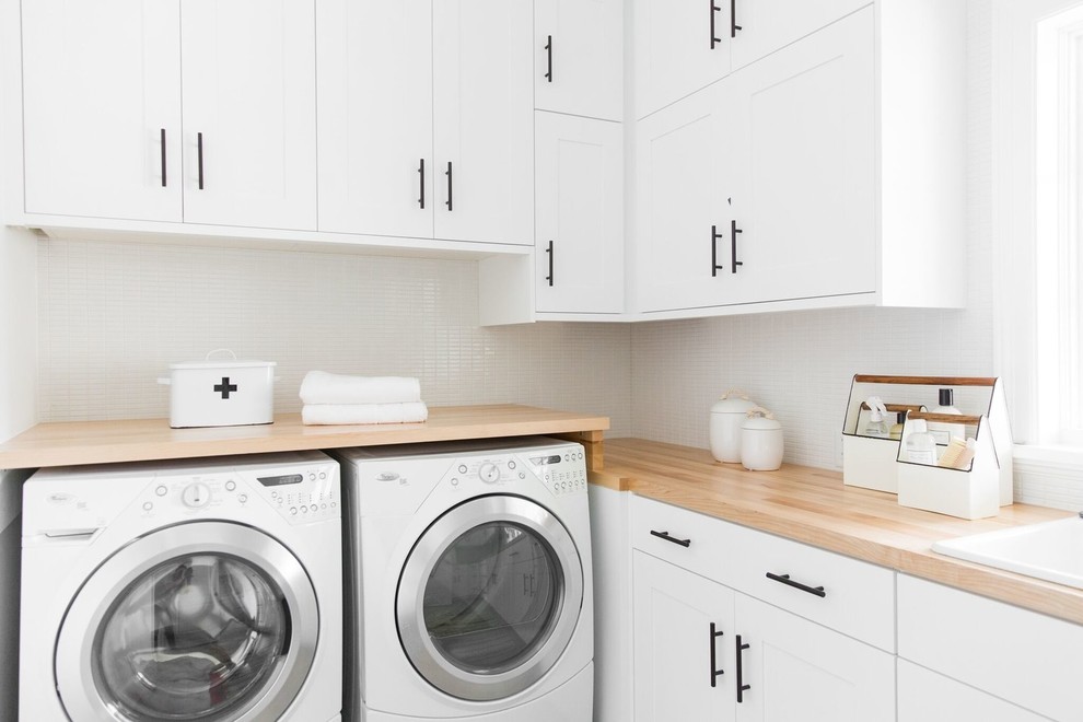 Foto di una sala lavanderia chic di medie dimensioni con lavello da incasso, ante in stile shaker, ante bianche, top in legno, pareti bianche e lavatrice e asciugatrice affiancate