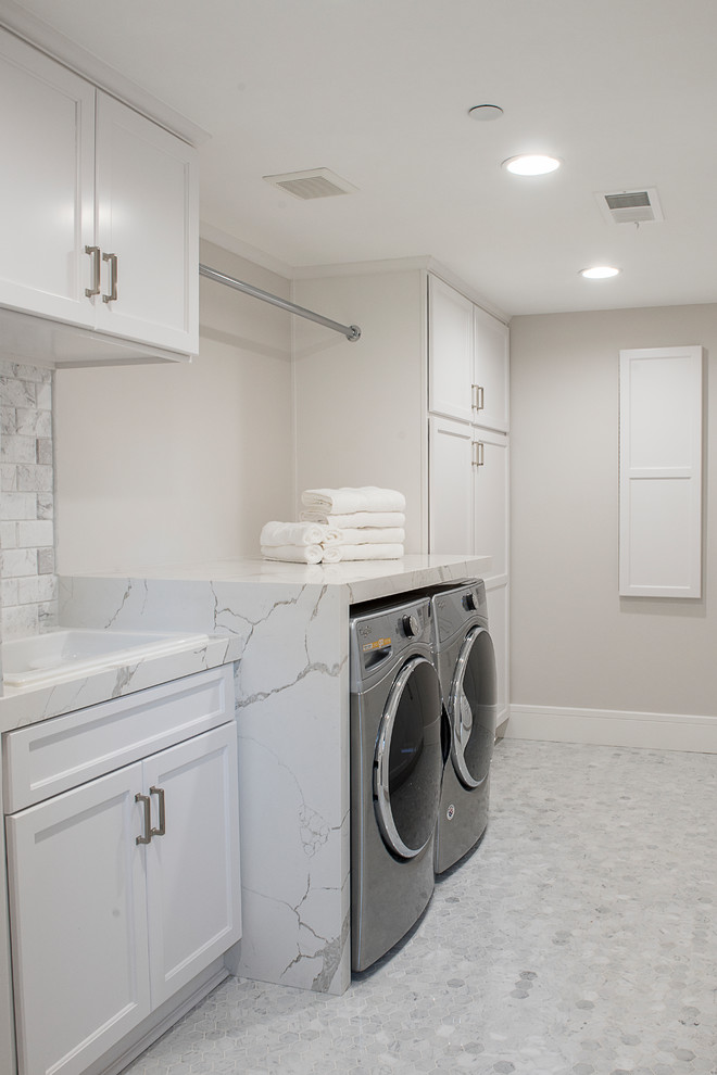 Imagen de cuarto de lavado actual de tamaño medio con armarios estilo shaker, puertas de armario blancas, encimera de cuarzo compacto, lavadora y secadora juntas, encimeras blancas, suelo de mármol y suelo gris