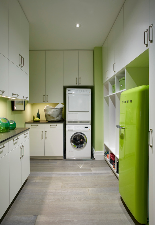 Dedicated laundry room - mid-sized transitional u-shaped dark wood floor dedicated laundry room idea in New York with flat-panel cabinets, white cabinets, quartz countertops, green walls and a stacked washer/dryer