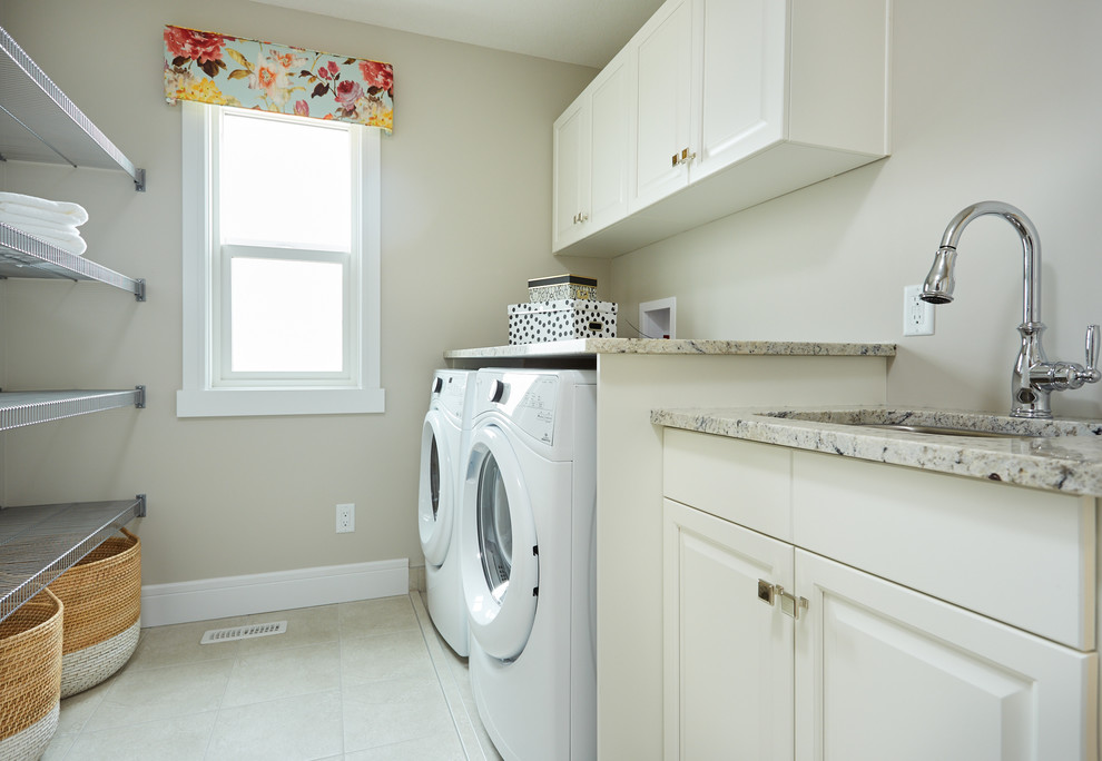 エドモントンにある広いトランジショナルスタイルのおしゃれな洗濯室 (I型、アンダーカウンターシンク、レイズドパネル扉のキャビネット、白いキャビネット、御影石カウンター、ベージュの壁、淡色無垢フローリング、左右配置の洗濯機・乾燥機) の写真